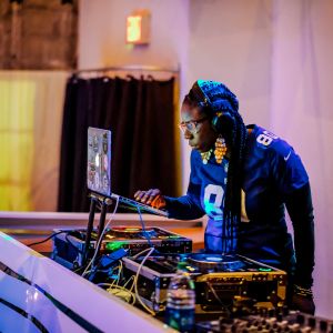 a music dj looking at a laptop connected to electronic turntables