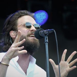 a bearded singer wearing sunglasses emotes into a microphone