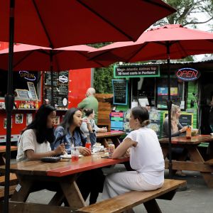 diners eating at a picnic table at an outdoor food cart pod