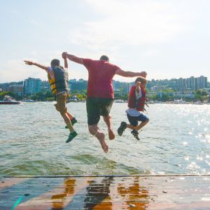 three people mid-jump into a river