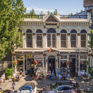 the facade of a large Irish pub with groups of people eating and drinking out front