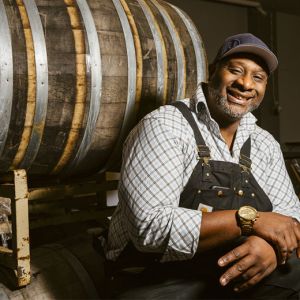 african american man smiles next to wine barrel