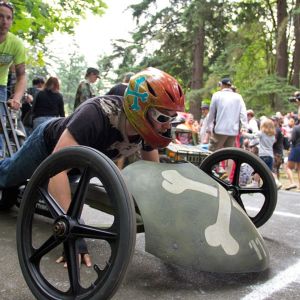 an adult prepares to race a skull and crossbones-styled soapbox