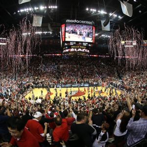 Streamers rain down over a basketball court and thousands of fans