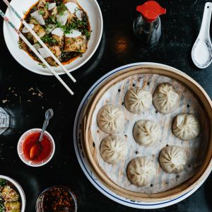 an overhead view of an array of dumplings, tofu and other Chinese dishes