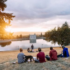 people enjoy a picnic at sunset looking out over a reservoir