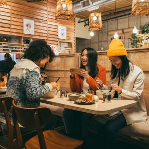 friends enjoy large bowls of Thai fare in a warmly lit restaurant
