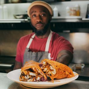 a chef serves a dish with the plate and food in focus