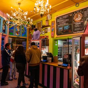 people stand in a lobby decorated with art, colors, and menus on the wall