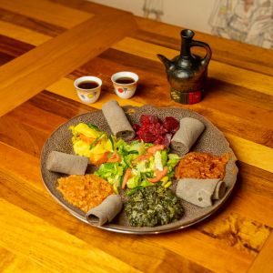 a large plate of colorful food, a pitcher and two teacups on a wooden table at Enat Kitchen in Portland