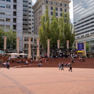 people sitting, walking in brick plaza with white columns