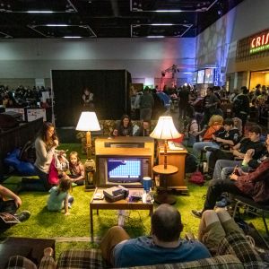 gamers and onlookers gather around a vintage television set in a living room set up at a gamer conference in Portland, Oregon