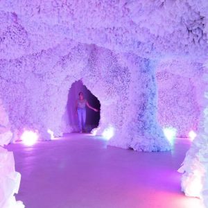 A person explores brightly lit, highly textured cave-like structure.