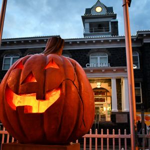 a giant pumpkin sculpture is lit on the inside sitting in front of a town hall building