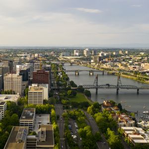 aerial view of downtown area with buildings and roadways, bridges crossing a river to a smaller set of buildings that expand into the distance