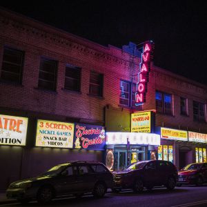 nighttime street view of neon signs adorning a historic neighborhood theater and arcade