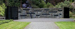 A person stands in front of a memorial made of stone bricks