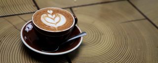 cup of coffee with latte art sitting on a wooden coffee table