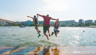 three people mid-jump into a river