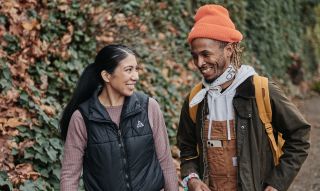 two people smile at each other while walking in the woods