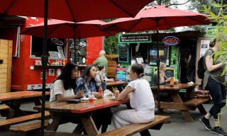 diners eating at a picnic table at an outdoor food cart pod