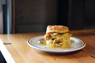 A biscuit sandwich with egg, sausage and melted cheese on a plate