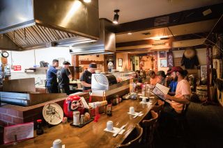 Customers sit around a bar while sushi chefs work