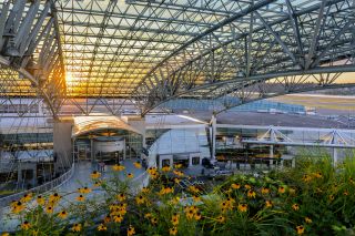 metal and glass canopy over Portland Airport entrances with flowers blooming in the foreground