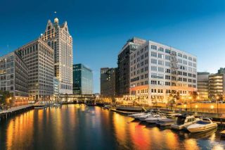 large buildings with street lights reflecting on the river at dusk