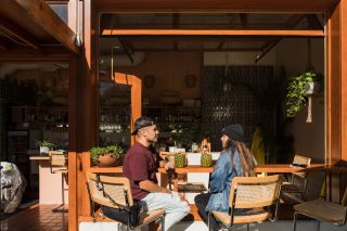 Two people enjoy alcoholic beverages on a sunny patio.