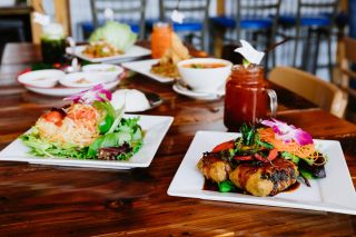 a noodle salad and a dish of fried food with a beverage and several other dishes in the background at Kati Portland, a vegetarian and vegan Thai restaurant in Portland