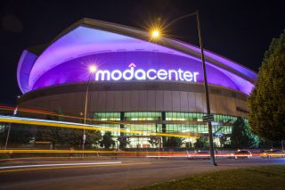 purple lights illuminate the Moda Center as traffic in streaks of light zoom by