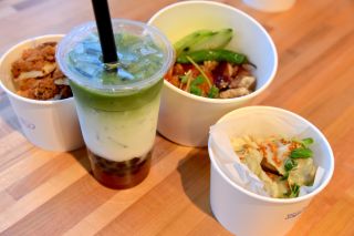 containers with food and a boba tea drink are arranged on a table