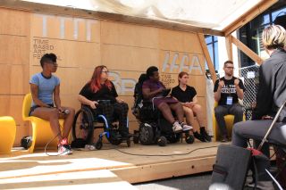 people on a stage look to an ASL interpreter during a artist presentation and conversation