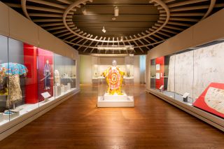 native American artworks in a brightly-lit museum gallery, including traditional and contemporary robes and art