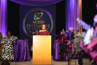 A woman stands at a podium accepting an award.