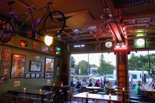 colorful décor surrounding empty indoor bar tables with crowded patio tables in the background