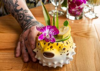 a drink with various tropical garnishes made in a glass shaped like a blowfish