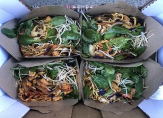 Four takeout boxes of noodles, mixed vegetables, and spinach.