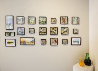 Collection of small framed art hanging on wall of J. Pepin Art Gallery