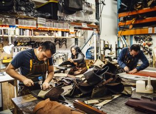 people working on leather hand-made items at workbenches