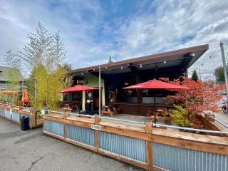 An outdoor patio with a low fence surrounding some picnic tables with umbrellas.