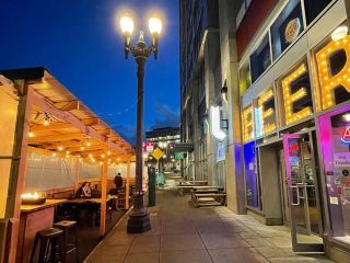 Streetside patio seating that is covered with table heaters.