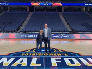 A man and a woman stand on the basketball court where the 2019 Women's Final Four was played.