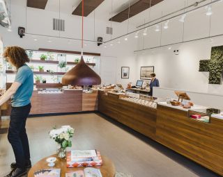 Person shopping at a dispensary stocked with shelves full of cannabis products.