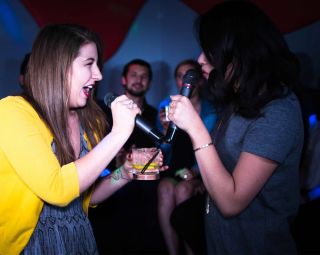 two women singing into microphones