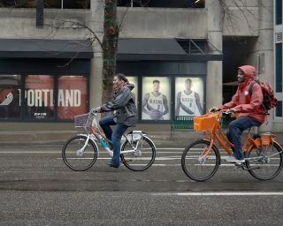 Cyclists bike through downtown Portland on bikes designed for Biketown Culture Collection