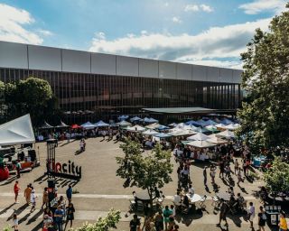 areal view of market stalls in the parking lot of a large building