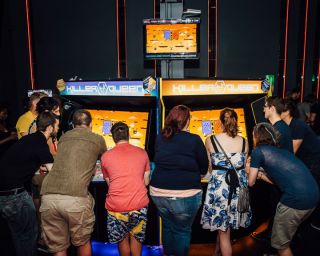 group of people surround the Killer Queen, a 10-player real-time strategy game