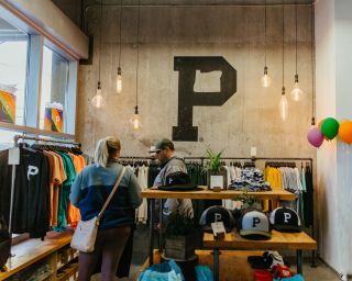 two people browse through racks of clothing at a shop